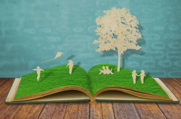 Papír řez děti hry na staré trávy knihu — Stock fotografie