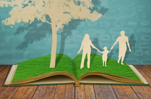 Corte de papel de símbolo da família sob a árvore no velho livro de grama — Fotografia de Stock