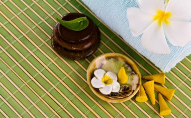 Frangipani çiçekler ve yapraklar zen taşlar ile bir bambu hasır