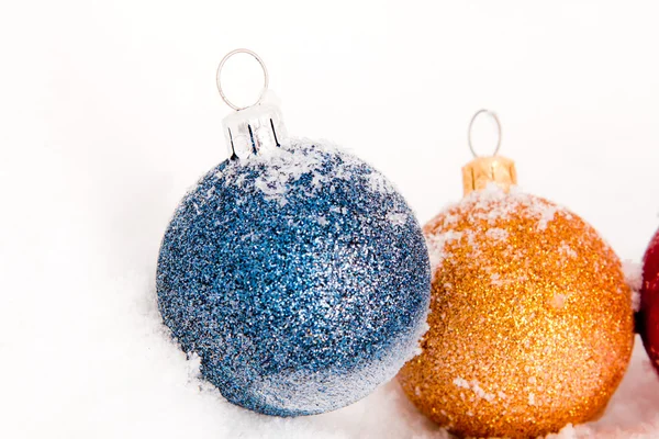 Голубые, красные и золотые рождественские шары со снегом — стоковое фото