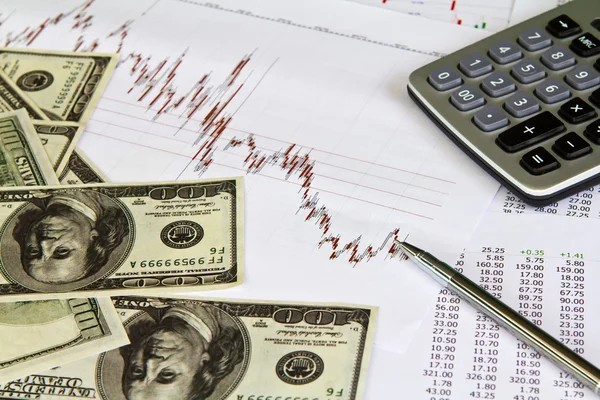 Ручка, калькулятор и доллары на финансовых графиках — стоковое фото