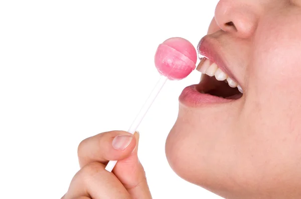 Woman licking a pink shiny lollipop on white background. — Stock Photo, Image