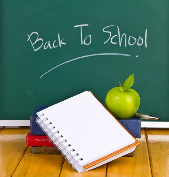 Yeşil elma ve kitaplar ile kara tahta üzerinde yazılı okula dönüş — Stok fotoğraf
