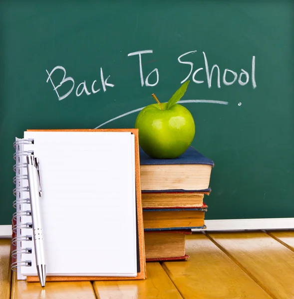 Yeşil elma ve kitaplar ile kara tahta üzerinde yazılı okula dönüş — Stok fotoğraf