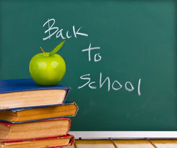 Back to school written on chalkboard with green apple and books — Stock Photo, Image