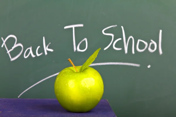 Voltar para a escola escrito em quadro-negro com maçã verde e livros — Fotografia de Stock