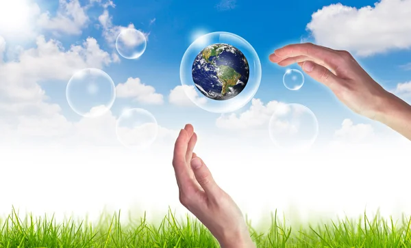Öko-Konzept: Globus mit der Hand in Blasen gegen Sonne und Wind halten — Stockfoto