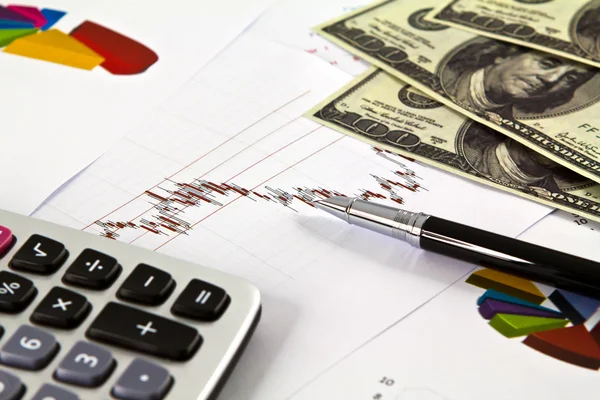 Pluma, calculadora y dólares en gráficos financieros — Foto de Stock