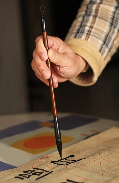 Een oude man praktiserende callingraphy met een borstel-pen Stockfoto