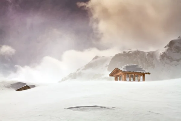 stock image Wooden cottage and snow covered huts in blizard at the peak of s