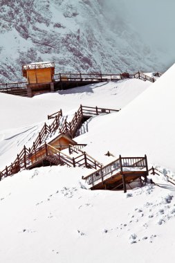 Wooden cottage on peak of Yulong Snow Mountain clipart