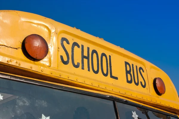 Frente de ônibus escolar amarelo contra o céu azul — Fotografia de Stock