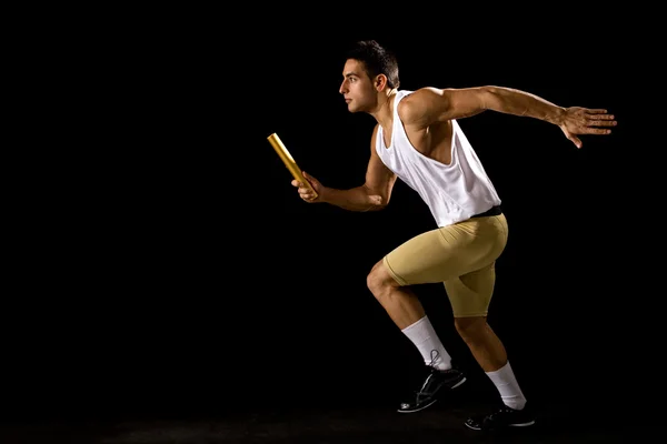 Relay racer in motion. Studio shot over black. — Stock Photo, Image