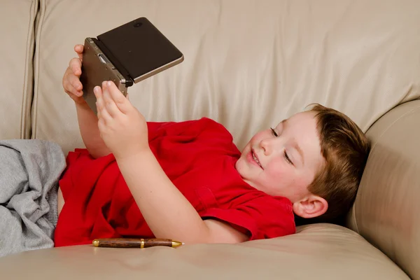 Концепція диванної картоплі хлопчика, який грає у відеоігри, відпочиваючи на дивані — стокове фото