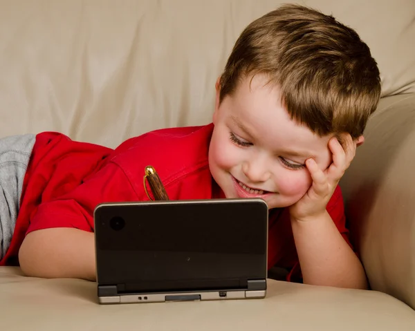 Koncept povalečem chlapce hrát video hry při odpočinku na pohovce — Stock fotografie
