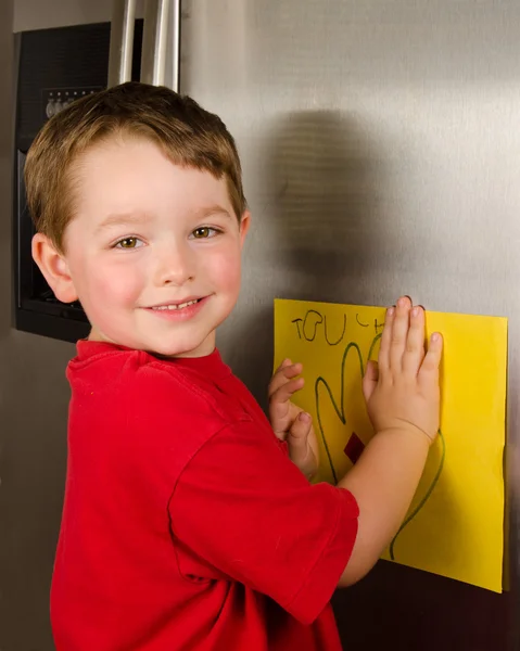 Child putting his art up on family refrigerator at home — Stock Photo, Image