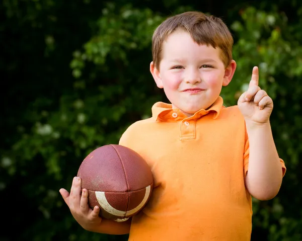 Ребенок с футболом празднует, показывая, что он номер 1 — стоковое фото