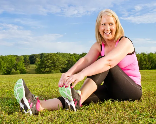 Mujer de mediana edad de 40 años que se estira para hacer ejercicio al aire libre —  Fotos de Stock
