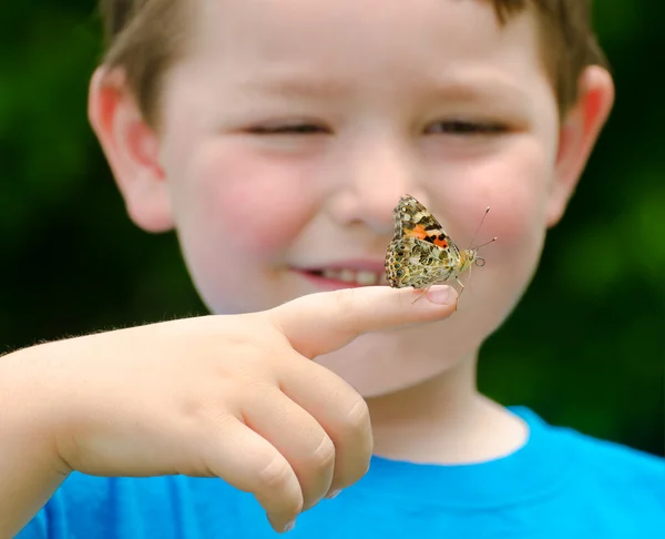 Spring concept with close up of a painted lady butterfly, Vanessa cardui, being held by child playing outdoors in nature — Stock Photo, Image