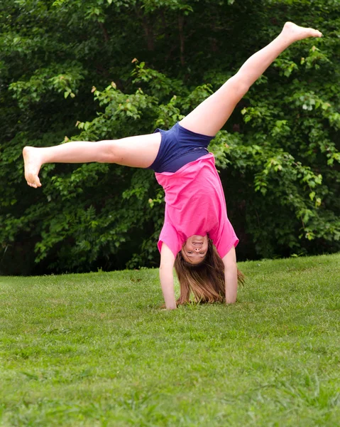 Young girl doing a cartwheel outdoors at park — Stock Photo, Image