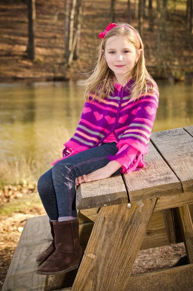 Retrato de invierno o principios de primavera de una niña bonita con poncho de punto en el parque — Foto de Stock