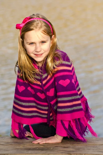 Inverno ou início da primavera retrato de menina bonita criança usando poncho de malha no parque — Fotografia de Stock