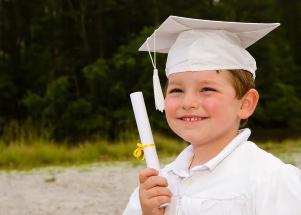 Молодий хлопчик з шапочкою і сукнею і сертифікатом для дошкільного випуску — стокове фото