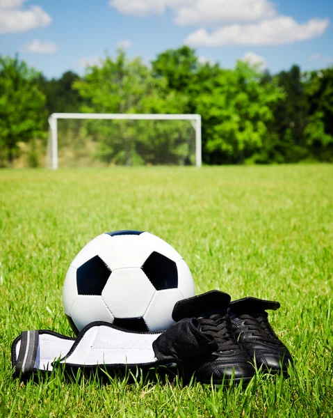 Child sports concept with soccer ball, cleats, shin guards on field with copy space — Stock Photo, Image