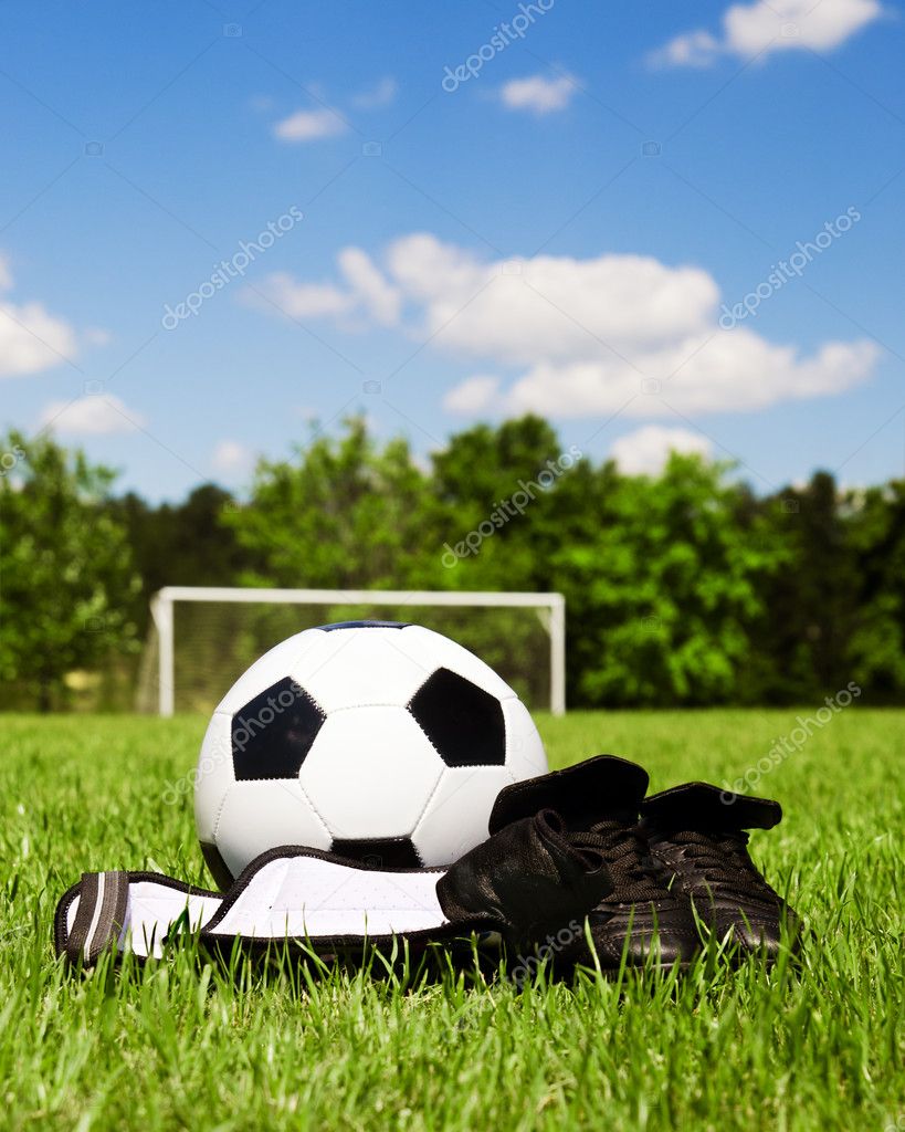 Child sports concept with soccer ball, cleats, shin guards on field ...