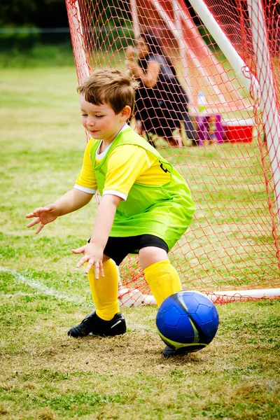 Мальчик играет в футбол во время матча организованной лиги — стоковое фото