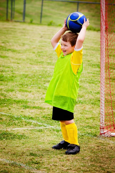 Menino jovem jogando futebol durante o jogo da liga organizada — Fotografia de Stock