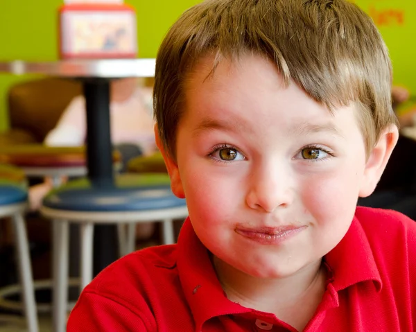 Unga pojkens ansikte täckt med choklad efter att ha ätit fryst yoghurt på fryst yoghurt eller glass shop — Stockfoto