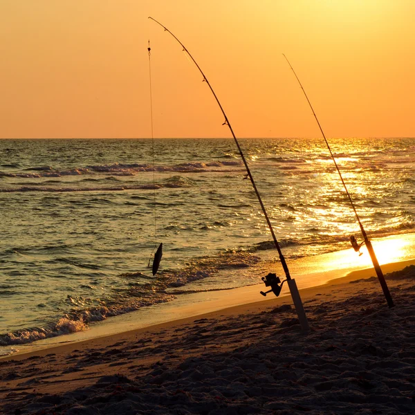 钓鱼杆在日落海滩上岸的设置 — 图库照片