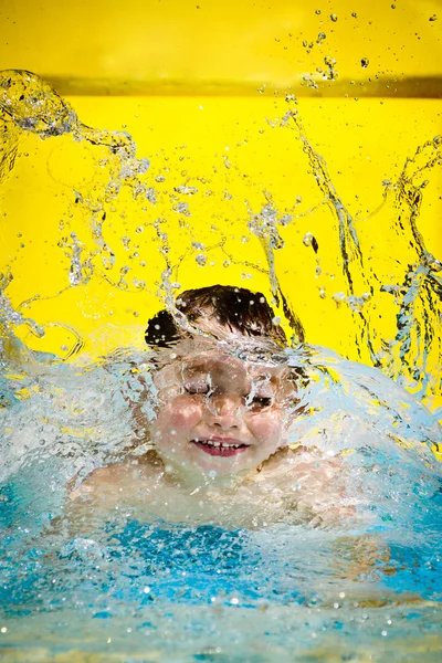 Młody chłopak lub dziecko ma zabawy, przelewanie w basenie po zejściu w dół zjeżdżalnią latem z kopia miejsce — Zdjęcie stockowe