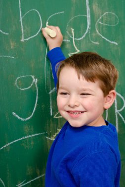 Portrait of young boy after writing on chalkboard for school homework clipart