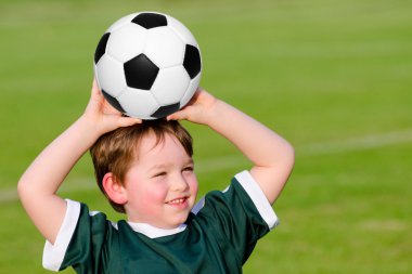 Young boy playing soccer in organized league game clipart