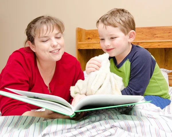 Moeder leest verhaaltje aan jonge jongen in zijn kamer 's nachts — Stockfoto