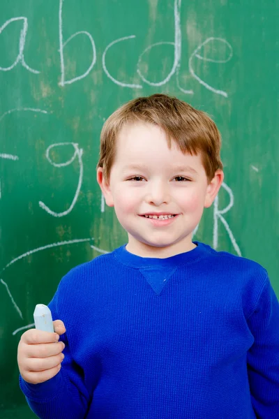 Portrait of young boy after writing on chalkboard for school homework — Stock Photo, Image