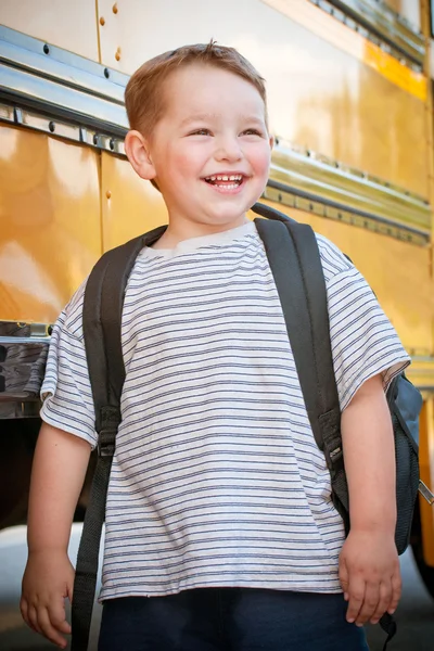 Glad ung pojke framför skolbussen går tillbaka till skolan — Stockfoto