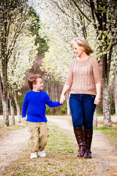 Mother and son at park during spring with flowering trees — Stock Photo, Image