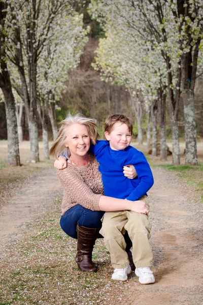 Mother and son at park during spring with flowering trees — Stock Photo, Image