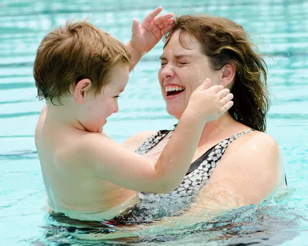 Madre e figlio rinfrescarsi giocando in piscina nella calda giornata estiva — Foto Stock