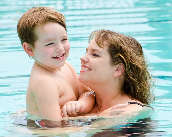 Madre e hijo se refrescan jugando en la piscina en el caluroso día de verano — Foto de Stock