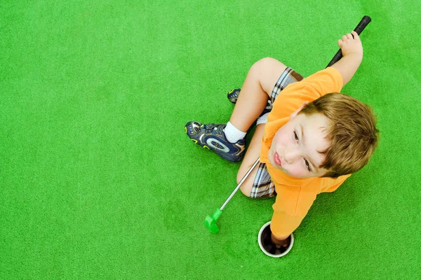 Giovane ragazzo gioca a mini golf su putt putt course . — Foto Stock