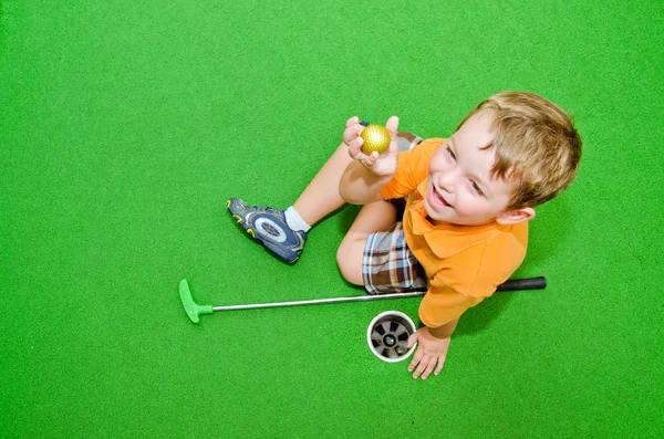 Jonge jongen speelt Minigolf op putt-putt cursus. — Stockfoto