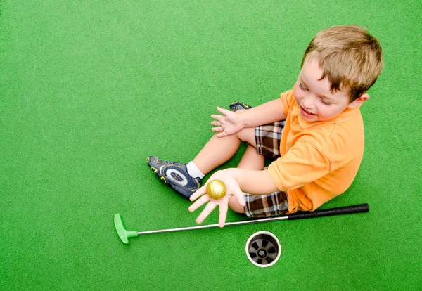 Young boy plays mini golf on putt putt course. — Stock Photo, Image