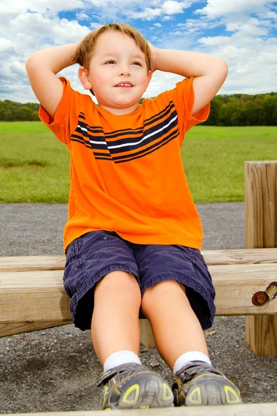 Young boy does sit-ups while exercising outdoors at park — Stock Photo, Image