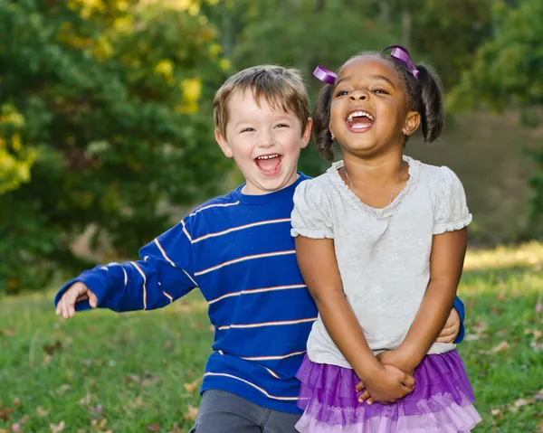 Молодая афро-американская девочка и белый мальчик играют вместе в парке — стоковое фото