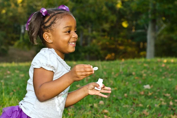 Joven afroamericana jugando con burbujas en el parque — Foto de Stock