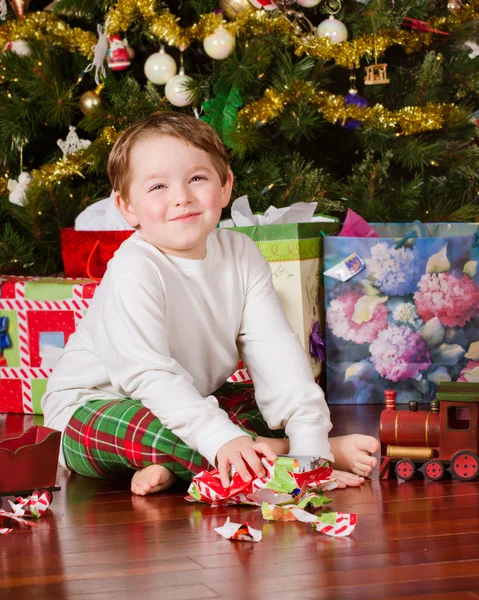 Young boy unwrapping presents on Christmas morning — Stock Photo, Image